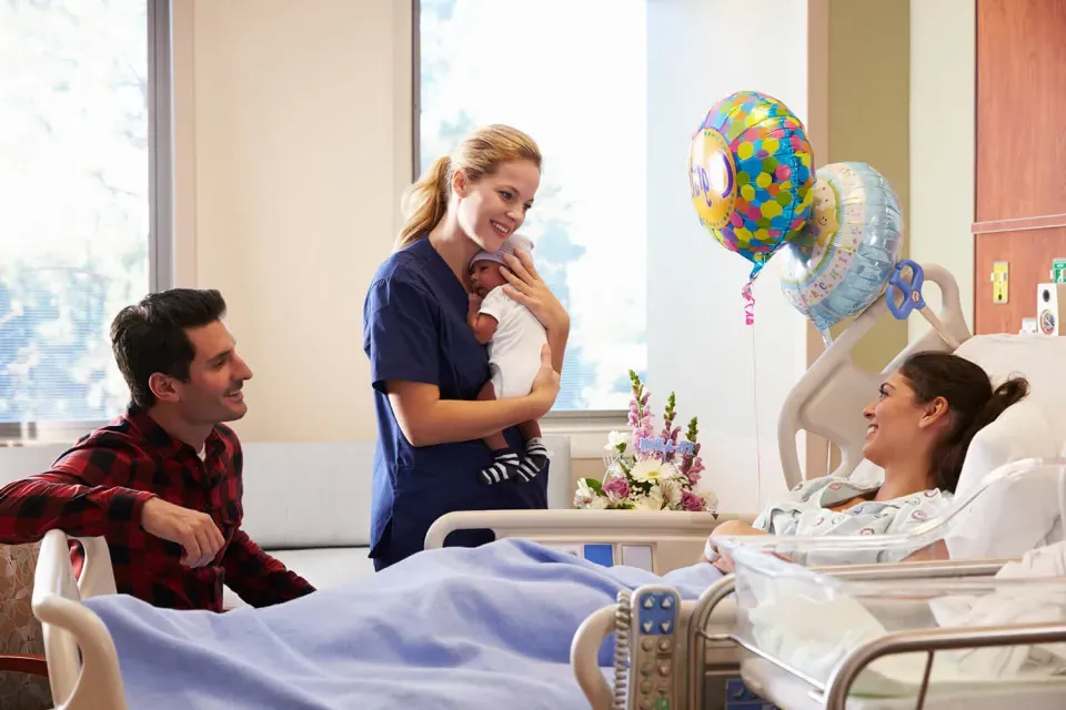 分娩护士 Holding Infant 和 Smiling with New Parents